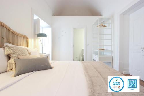 a white bedroom with a large white bed with pillows at Lavradores Boutique Guesthouse in Évora