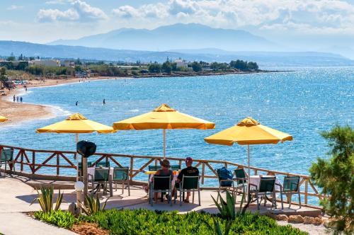 people sitting in chairs under umbrellas at a beach at Alkionis Beach Hotel Apartments in Sfakaki