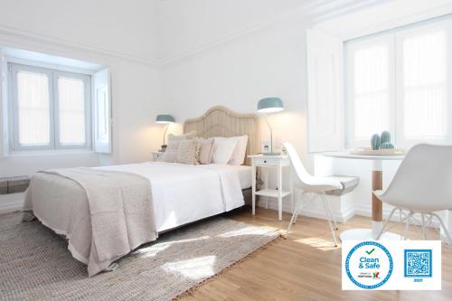 a white bedroom with a bed and a table and a chair at Lavradores Boutique Guesthouse in Évora