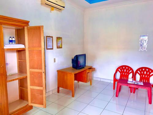 a room with a desk with a television and two chairs at Hotel Rembulan in Tebingtinggi