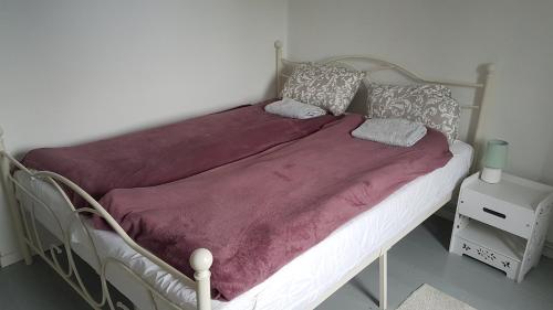 a bed with a purple blanket and pillows on it at Dom O Niebieskich Okiennicach in Gryfów Śląski
