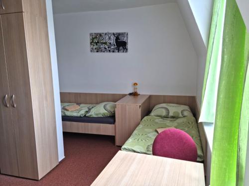 Habitación pequeña con 2 camas y silla rosa. en Veghouse - Penzion u pláže en Horní Bečva