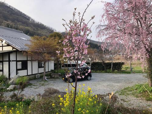 a car parked in front of a house with a flowering tree at フクロウの御宿 春日居館 in Isawa