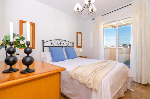 a bedroom with a bed with blue pillows and a window at WintowinRentals Pool, Sunny side & Free Parking. in Torre de Benagalbón