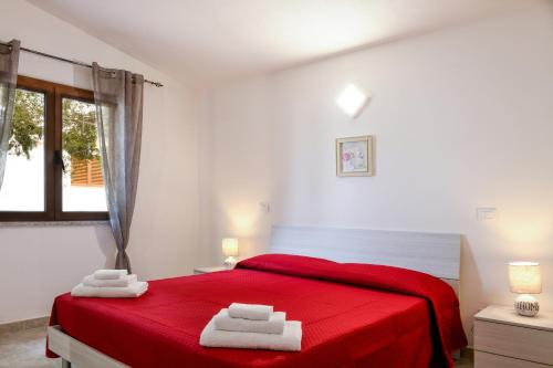 a bedroom with a red bed with two towels on it at Orosei Summer Holidays - Cala del Turco green house in Orosei