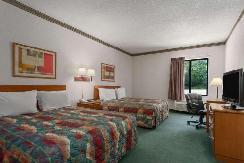 a hotel room with two beds and a flat screen tv at Days Inn by Wyndham Jefferson City in Jefferson City