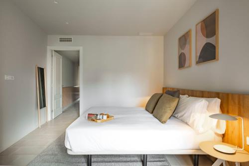 ein Schlafzimmer mit einem großen weißen Bett und einem Tisch in der Unterkunft Aspasios Garden Apartments in Barcelona