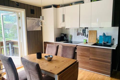 a kitchen with a wooden table with chairs and a counter at Super sentral, flott og solrik leilighet i sentrum in Hemsedal