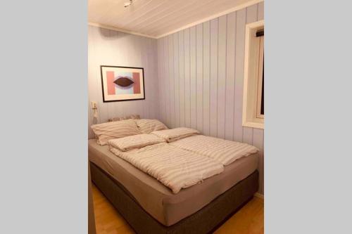 a bedroom with a bed with white sheets and a window at Super sentral, flott og solrik leilighet i sentrum in Hemsedal