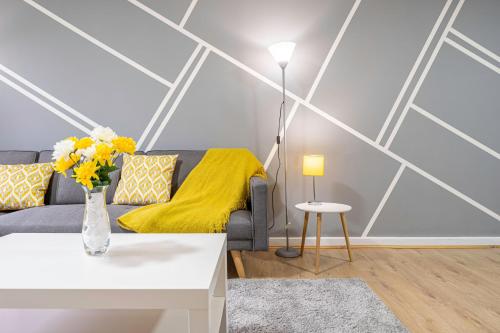 a living room with a couch and a yellow blanket at Riley House Spacious City Apartment in Coventry