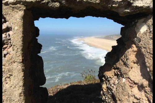 a view of a beach through a rock window at baleal penthouse in Ferrel