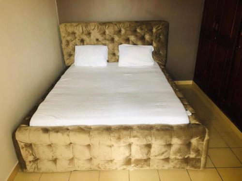 a bed with a tufted headboard and white sheets at Appartements meublés Sorel in Douala