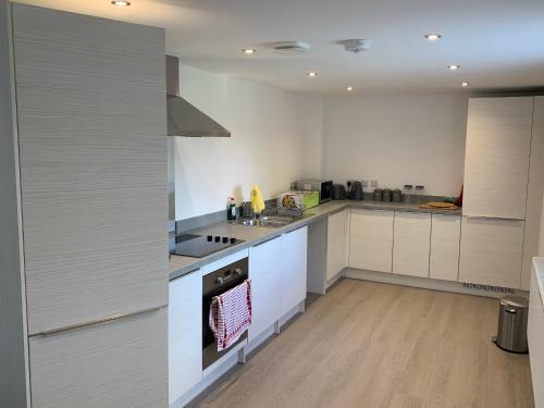 a kitchen with white cabinets and a stove top oven at Stunning Central Alnwick Two Floor Apartment in Alnwick