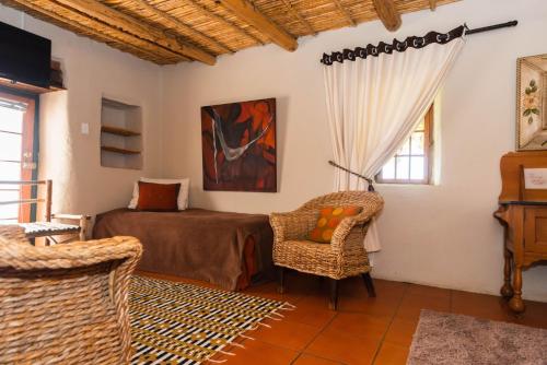 a bedroom with a bed and a chair in a room at Melkboomsdrift Guest House & Conference Centre in Vredendal