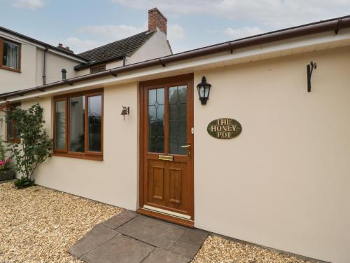 a white house with a wooden door and a sign on it at The Honey Pot in Chepstow