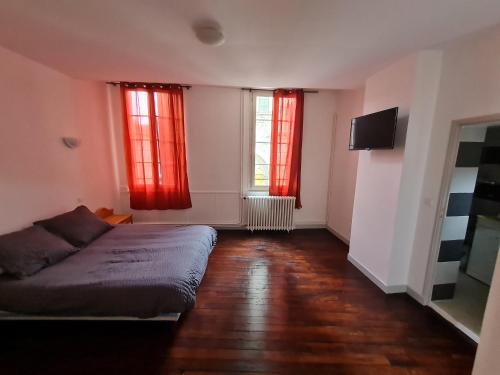 a bedroom with a bed and two windows with red curtains at LE COMMERCE in Pont-sur-Yonne
