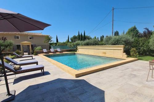 - une piscine dans une cour avec des chaises et un parasol dans l'établissement Le Cabanon de Nans. Gîte de charme en Provence., à Grans