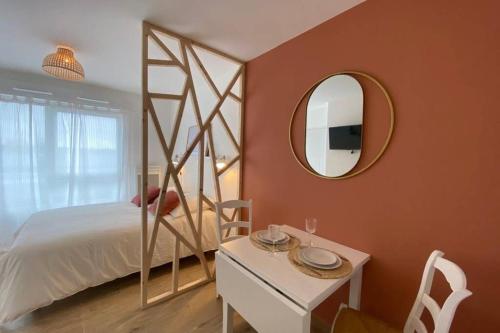 een slaapkamer met een bed, een spiegel en een tafel bij Héol in Saint-Malo