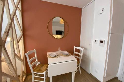 een eetkamer met een tafel en stoelen en een spiegel bij Héol in Saint-Malo
