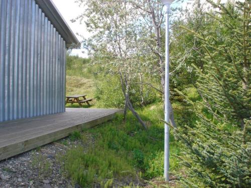 a wooden deck with a picnic table in the woods at Vinland Guesthouse in Egilsstadir