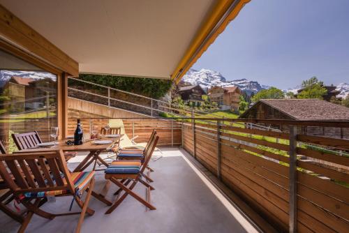 a balcony with chairs and a table with a view of mountains at Chalet Am Acher 3 in Wengen