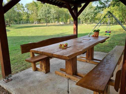 a wooden picnic table with a bowl of fruit and a swing at APARTMAN DEDA in Rakovica