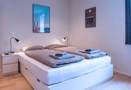 a bedroom with a white bed with towels on it at HITrental Central Station Apartment in Zürich