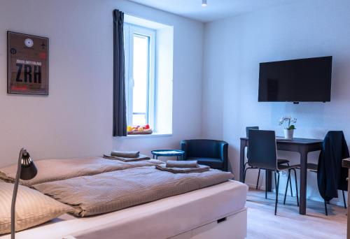 two beds in a room with a desk and a table at HITrental Central Station Apartment in Zürich