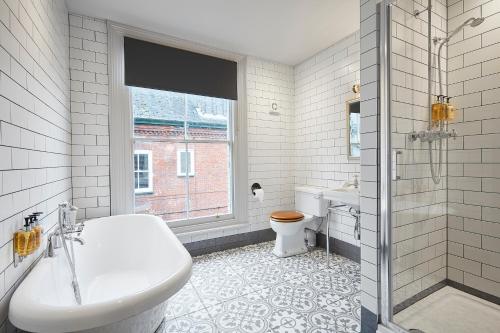 a bathroom with a tub and a toilet and a sink at The Georgian Townhouse in Norwich