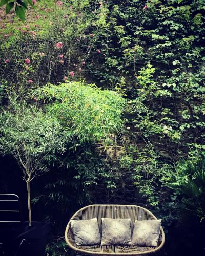 a rattan bench sitting in front of a bush at Léhontine in Dinan