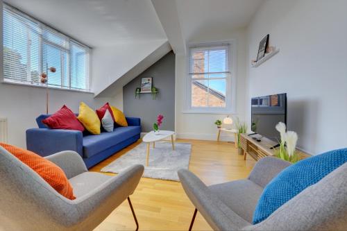 a living room with a blue couch and two chairs at Leamington Spa Warwick Place Apartments in Leamington Spa