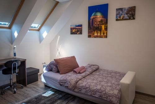 Un dormitorio con una cama y un escritorio y algunas fotos en Zsuka apartman free parking, en Pécs