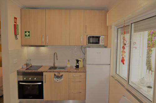 a kitchen with wooden cabinets and a white refrigerator at T0 Junto a Praia de Vale Centeanes / Carvoeiro in Lagoa
