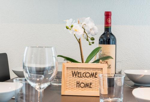 a bottle of wine and a vase with a flower on a table at HITrental Central Station Apartment in Zürich