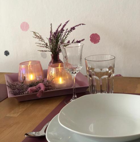 a table with two candles and a plate and glasses at Christianes Apartment - Ebstorf in Ebstorf