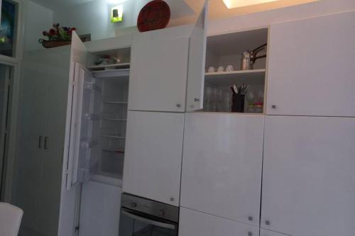 cocina con armarios blancos y puerta abierta en Casa Bianca, en Kalymnos