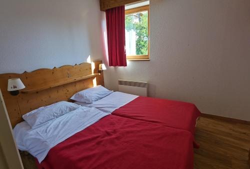a bedroom with a red and white bed with a window at CHAMROUSSE-SPORT&DETENTE appartement 6 couchages avec superbe vue in Chamrousse