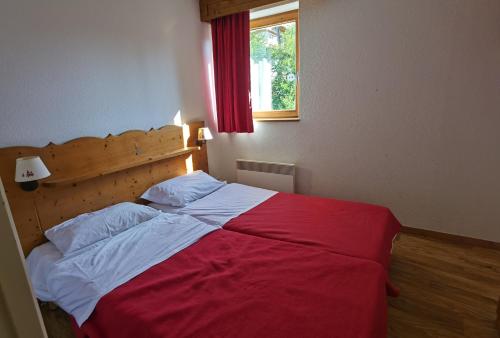 Un dormitorio con una cama roja y blanca y una ventana en CHAMROUSSE-SPORT&DETENTE appartement 6 couchages avec superbe vue, en Chamrousse