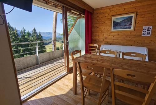 a room with a table and chairs and a balcony at CHAMROUSSE-SPORT&DETENTE appartement 6 couchages avec superbe vue in Chamrousse