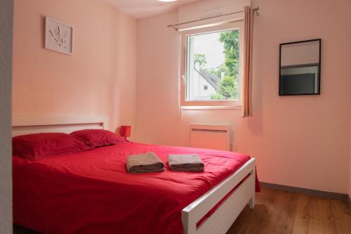 een slaapkamer met een rood bed en 2 handdoeken erop bij FONTANES in Niort