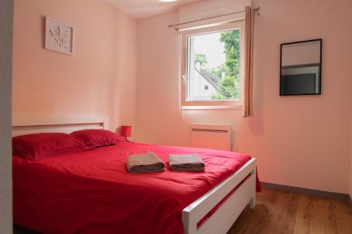 Un dormitorio con una cama roja con dos toallas encima. en FONTANES, en Niort
