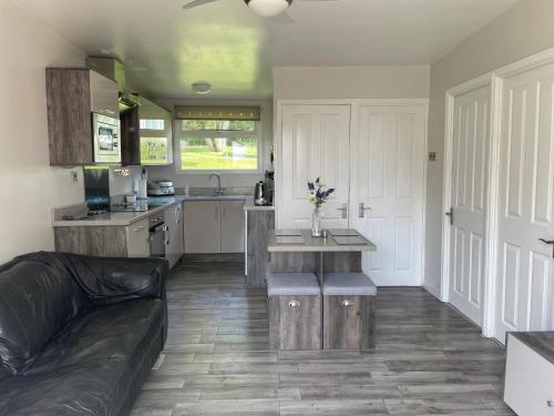 un soggiorno con divano e cucina di JJs Lodge Holiday Home 14 The Park Bude a Kilkhampton