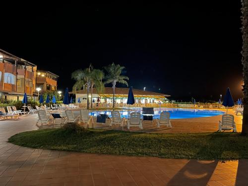 a group of chairs and a swimming pool at night at Grazioso appartamento al mare, in prov. di Matera in Marina di Pisticci