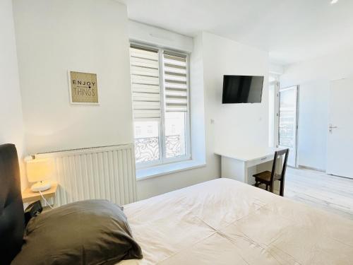 Dormitorio con cama, escritorio y TV en Residence Louis Quartier Gare, en Vittel