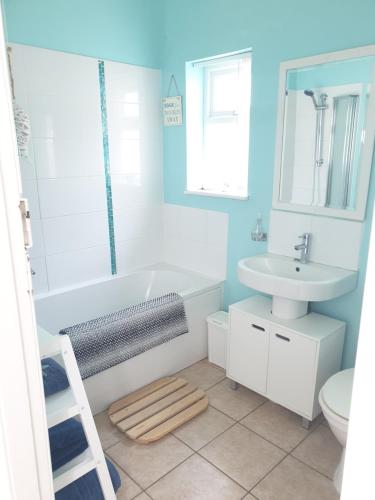 a bathroom with a white tub and a sink at Cosy seaside apartment in Woodhorn