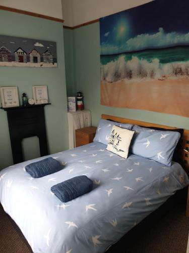 a bedroom with a bed with blue pillows on it at Cosy seaside apartment in Woodhorn