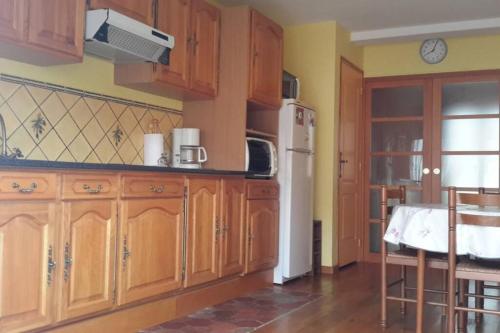 uma cozinha com armários de madeira e um frigorífico branco em Agréable logement dans petit village sud-essonne em Champcueil