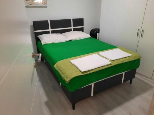 Una cama con sábanas verdes y almohadas blancas. en Apartman Centar Novi Grad, en Bosanski Novi
