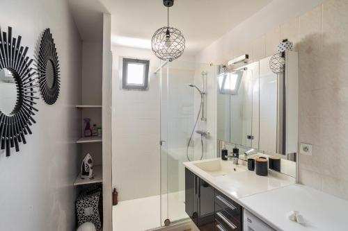 La salle de bains blanche est pourvue d'un lavabo et d'une douche. dans l'établissement Ty Marie by Cocoonr, à Rennes