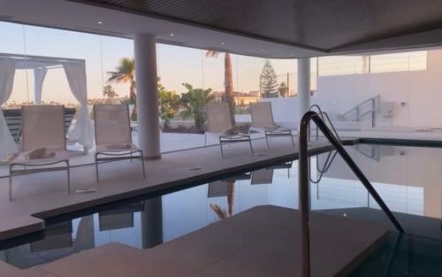 a pool with chairs and an umbrella next to a swimming pool at The View Luxury Vacation Apartment 2 in Fuengirola